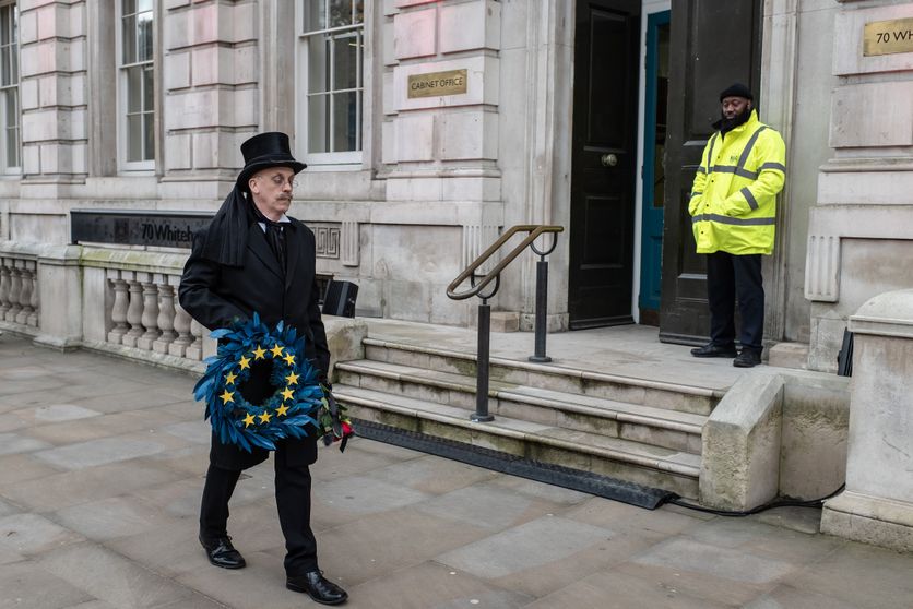 A man wearing an undertaker's attire, holding an 'EU' wreath, walks past the Cabinet Office on Whitehall. Réinitialisation des relations entre l’UE et le Royaume-Uni après le Brexit