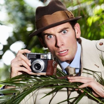 Retro spy man, camera and jungle for investigation, inspection or journalist with shock at job. Private investigator, secret photographer and retro paparazzi in trees, bush or leaves for surveillance Les morts manquent de correction – Une enquête malicieuse