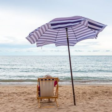 Traveler woman relax on the beach chair with umbrella at the beach. L’importance des vacances selon Jean Viard
