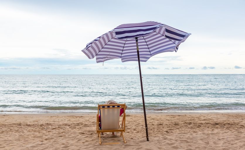 Traveler woman relax on the beach chair with umbrella at the beach. L’importance des vacances selon Jean Viard