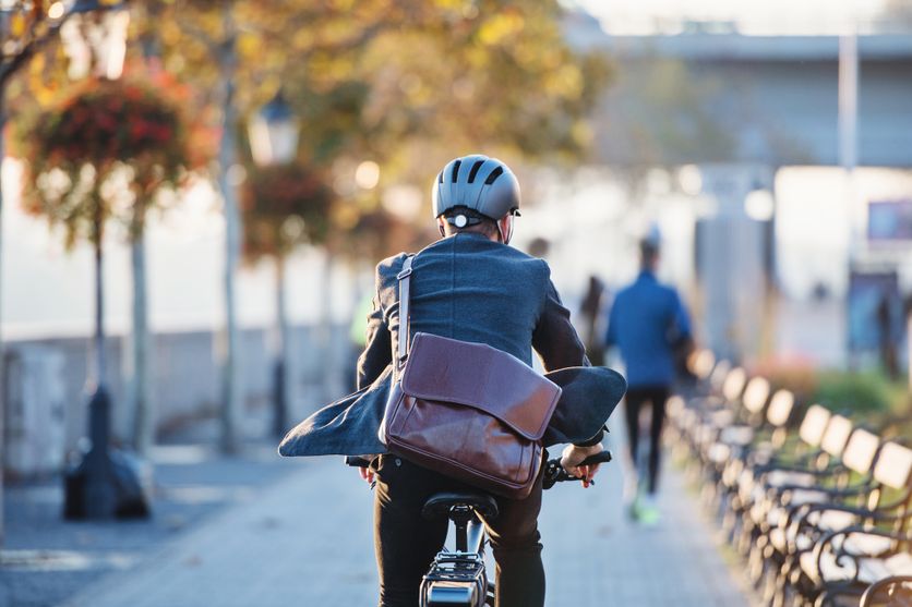 A rear view of businessman commuter with electric bicycle traveling to work in city. Débat sur le Port du Casque pour les Cyclistes en France