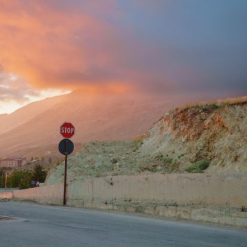 Serene sunset over mountain landscape with a stop sign and clouds Critique de ‘Une maison au Levant’ par Carole Dagher